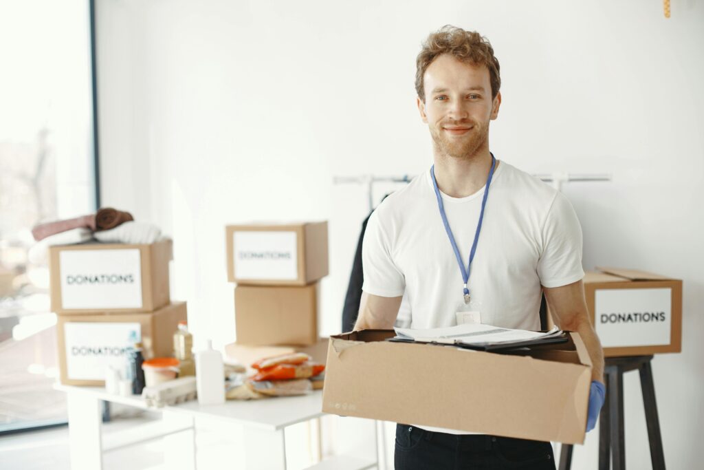 A man holding a box with donation boxes behind him.